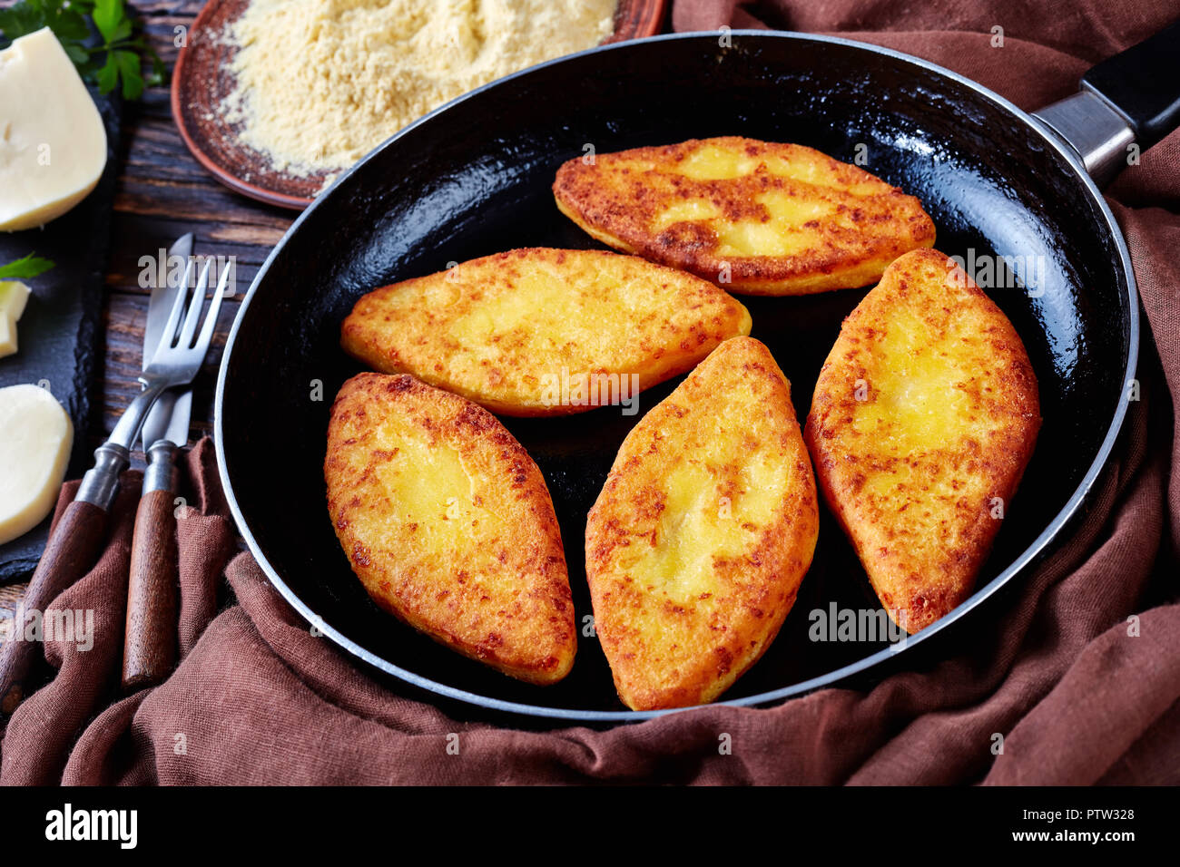 Chvishtari on a skillet with ingredients on a rustic table - cornmeal on a plate, sulguni cheese, view from above,   close-up Stock Photo