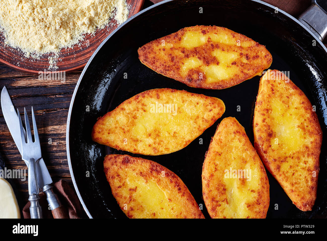 Chvishtari on a skillet with ingredients on a rustic table - cornmeal on a plate, sulguni cheese, view from above, close-up Stock Photo