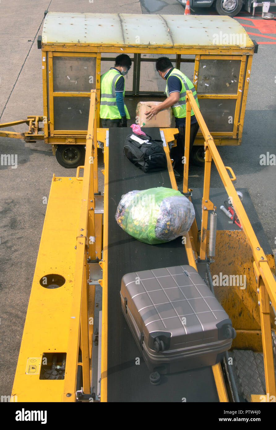 The men serve the conveyor belt with the luggage going from the plane. Stock Photo