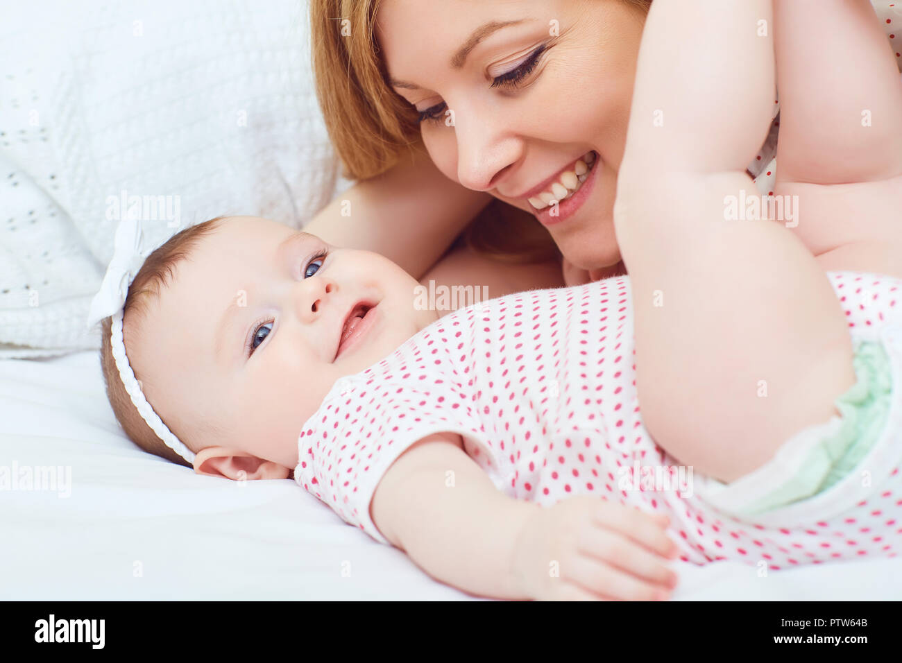 A happy mother with a baby plays on a bed.  Stock Photo