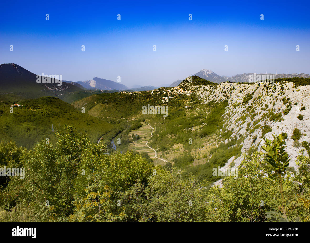 View of the mountain pass in Biokovo in Croatia. In the foreground are shrubs. The mountain range is in the background. Stock Photo