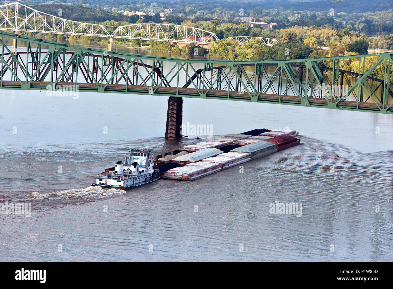Tugboat 'Allen P. Hall' pushing barges loaded with various covered products including coal, Parkersburg-Belpre cantilever bridge, Ohio River. Stock Photo