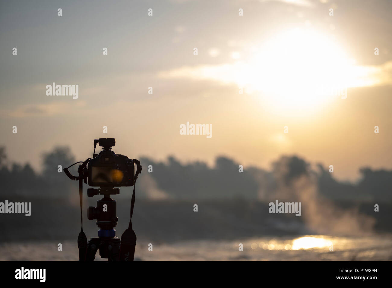 Camera on a tripod shooting at sunrise Stock Photo - Alamy