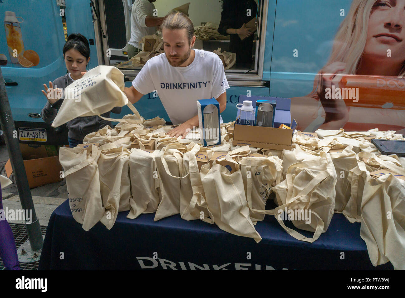 Workers hand out Drinkfinity kits containing a bottle and an assortment of flavored pods in New York on Saturday, October 6, 2018. Drinkfinity, which developed in Miami, uses flavored pods and a reusable vessel to create a 'better-for-you' beverage. The system reduces the use of disposable water bottles that enter the waste stream. Drinkfinity is backed by PepsiCo but operates independently as a start-up.  (© Richard B. Levine) Stock Photo