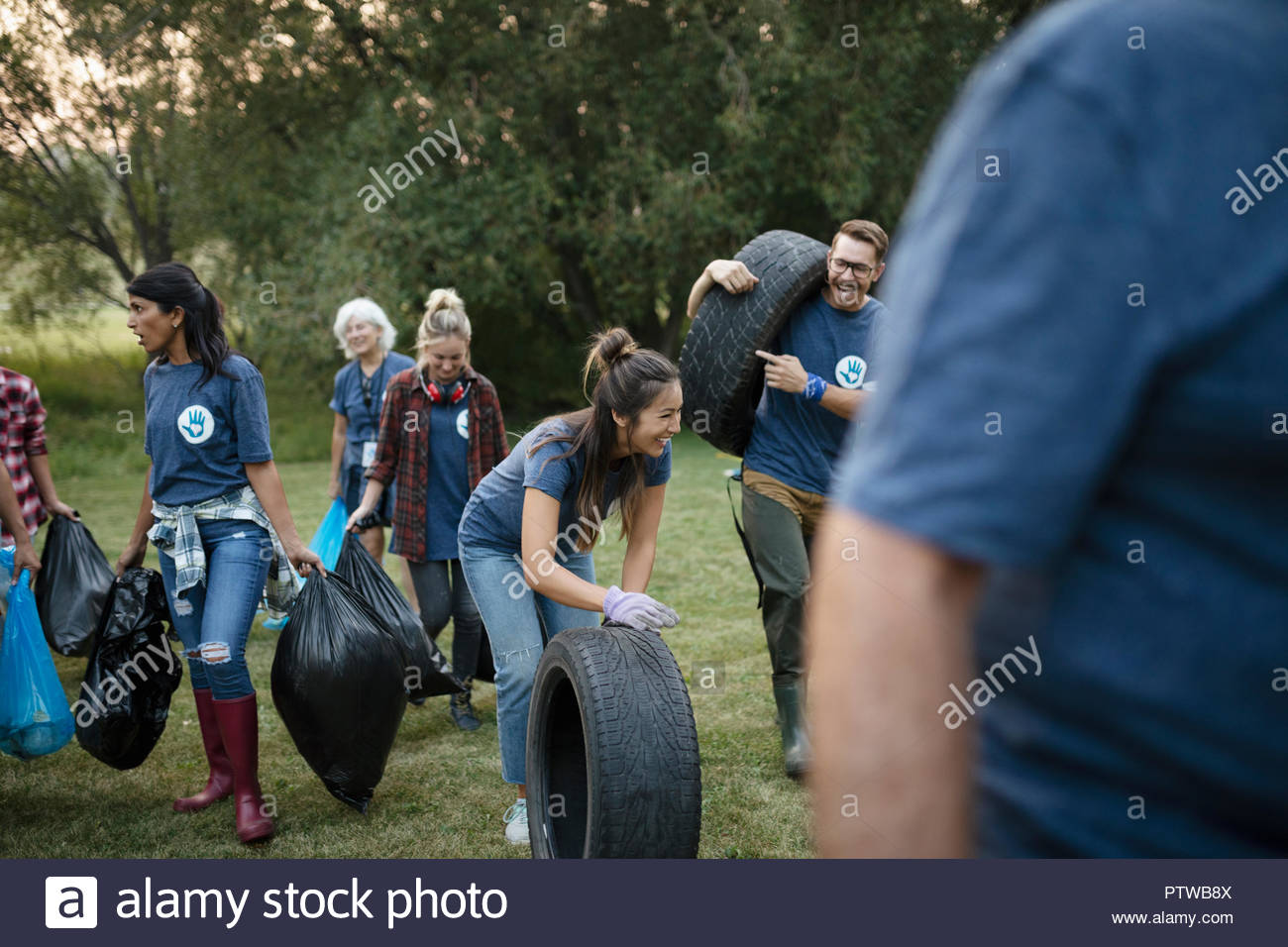 People volunteering, cleaning up garbage in park and rolling tires