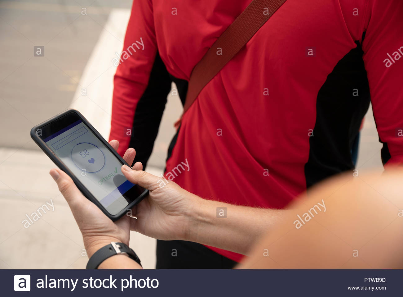 Female runner checking heart rate monitor app on smart phone Stock Photo