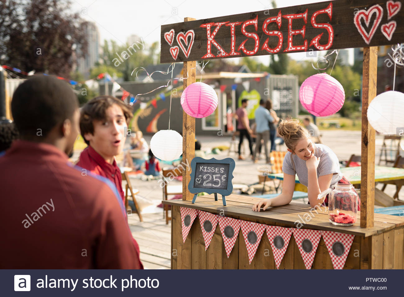 Teenage boys approaching kissing booth in park Stock Photo Alamy
