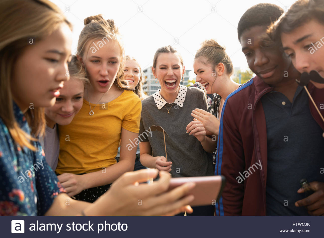 Playful teenagers with camera phone and mustache props Stock Photo