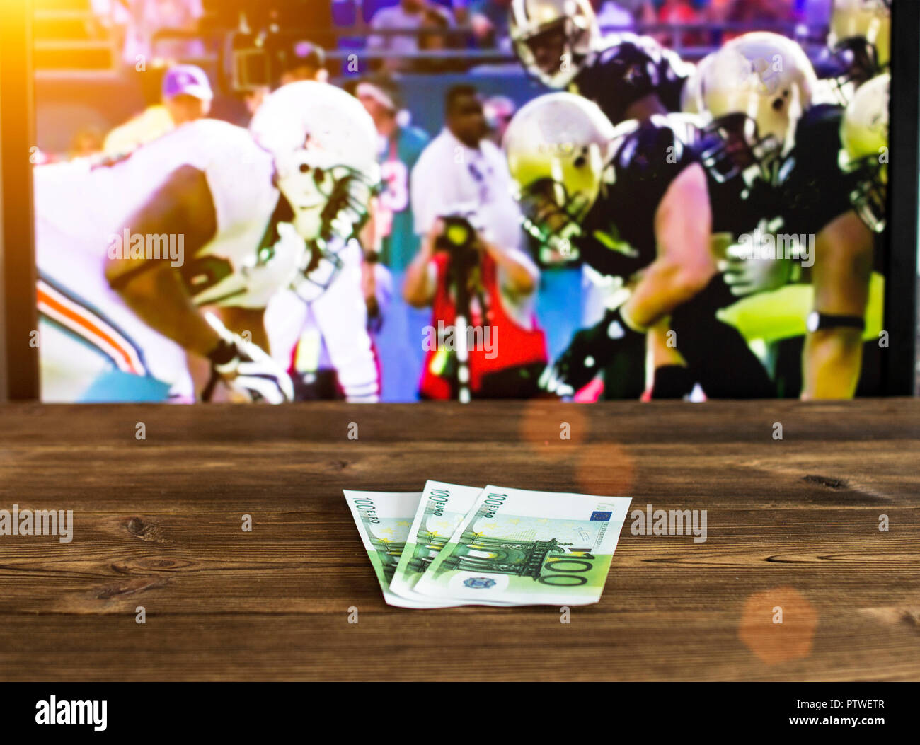 Euro money on the background of a TV on which American football is shown, betting on sports, euro and American football Stock Photo