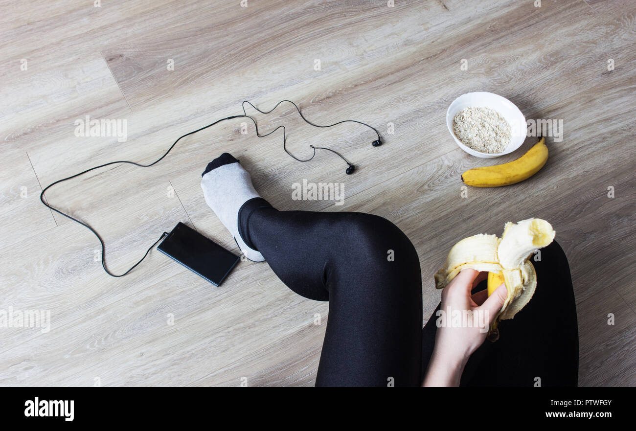 The girl eats a banana, porridge, a phone with headphones, a healthy