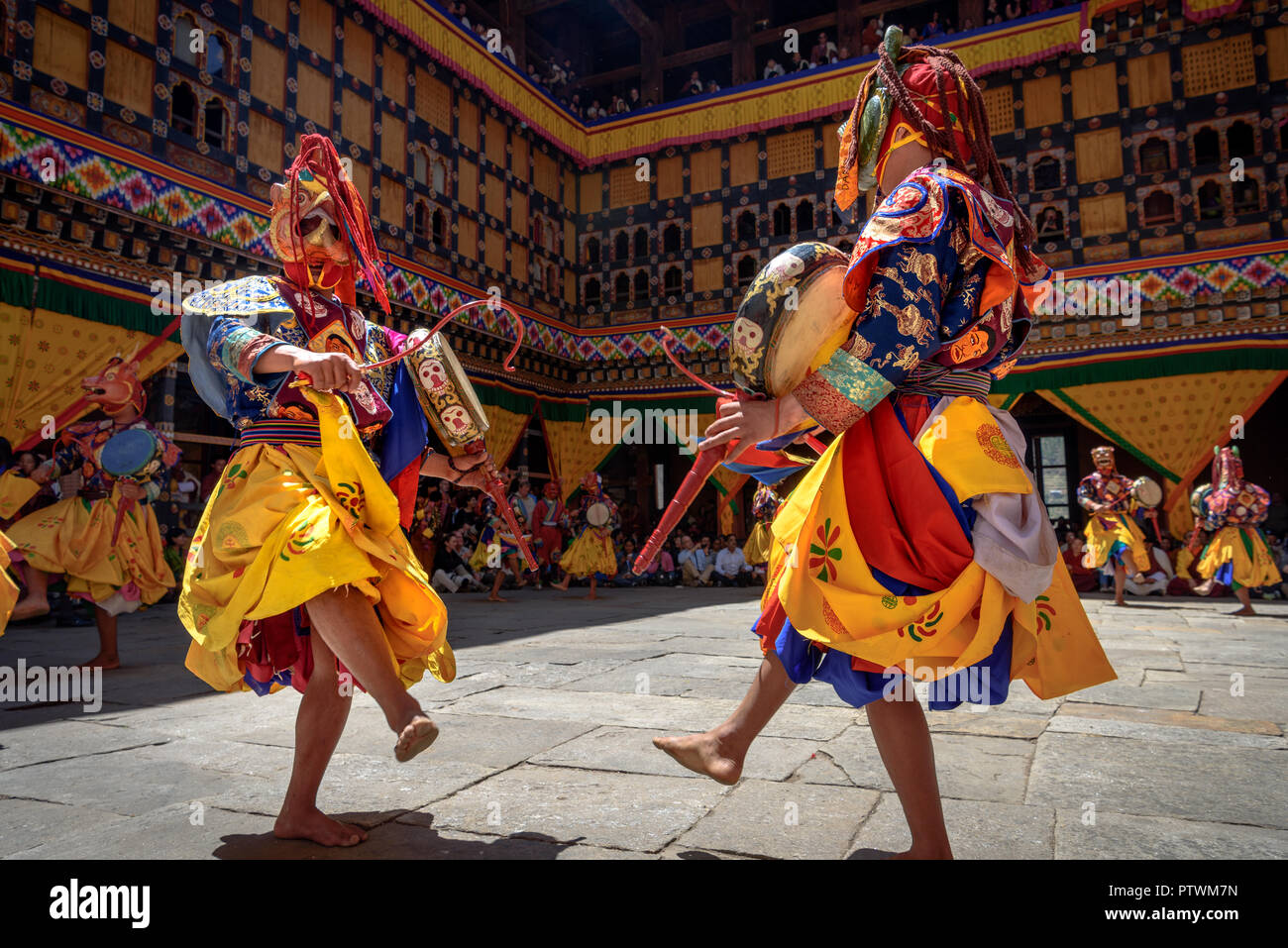 Buddhist Monk dancing and holding a drum at colourful mask dance at yearly buddhism Paro Tsechu festival in Bhutan monastery temple location. Stock Photo