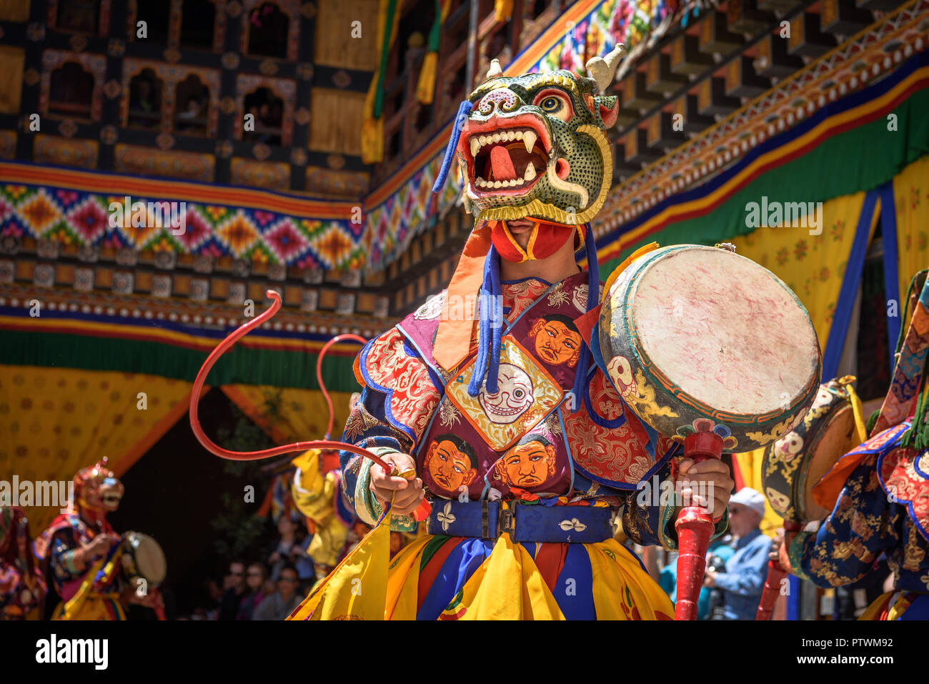 Buddhist Monk dancing and holding a drum at colourful mask dance at yearly buddhism Paro Tsechu festival in Bhutan monastery temple location. Stock Photo