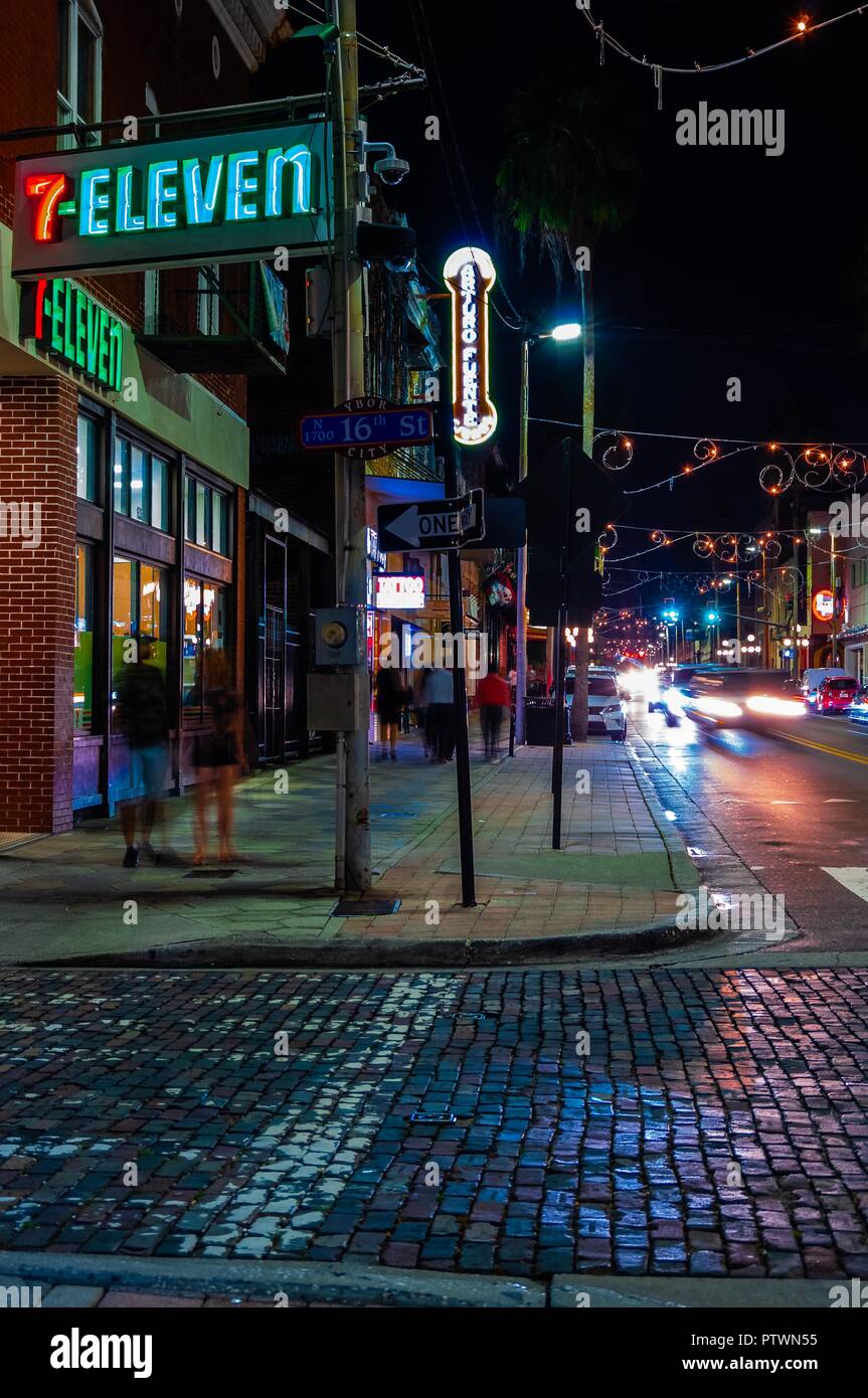 Tampa, FL--Oct 2, 2018; time exposure of pedestrians and cars traveling through red brick street of Ybor City Historic Cigar Factor District at night, Stock Photo