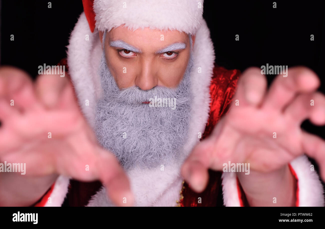 evil Santa Claus angrily looks at the camera on a dark background ...