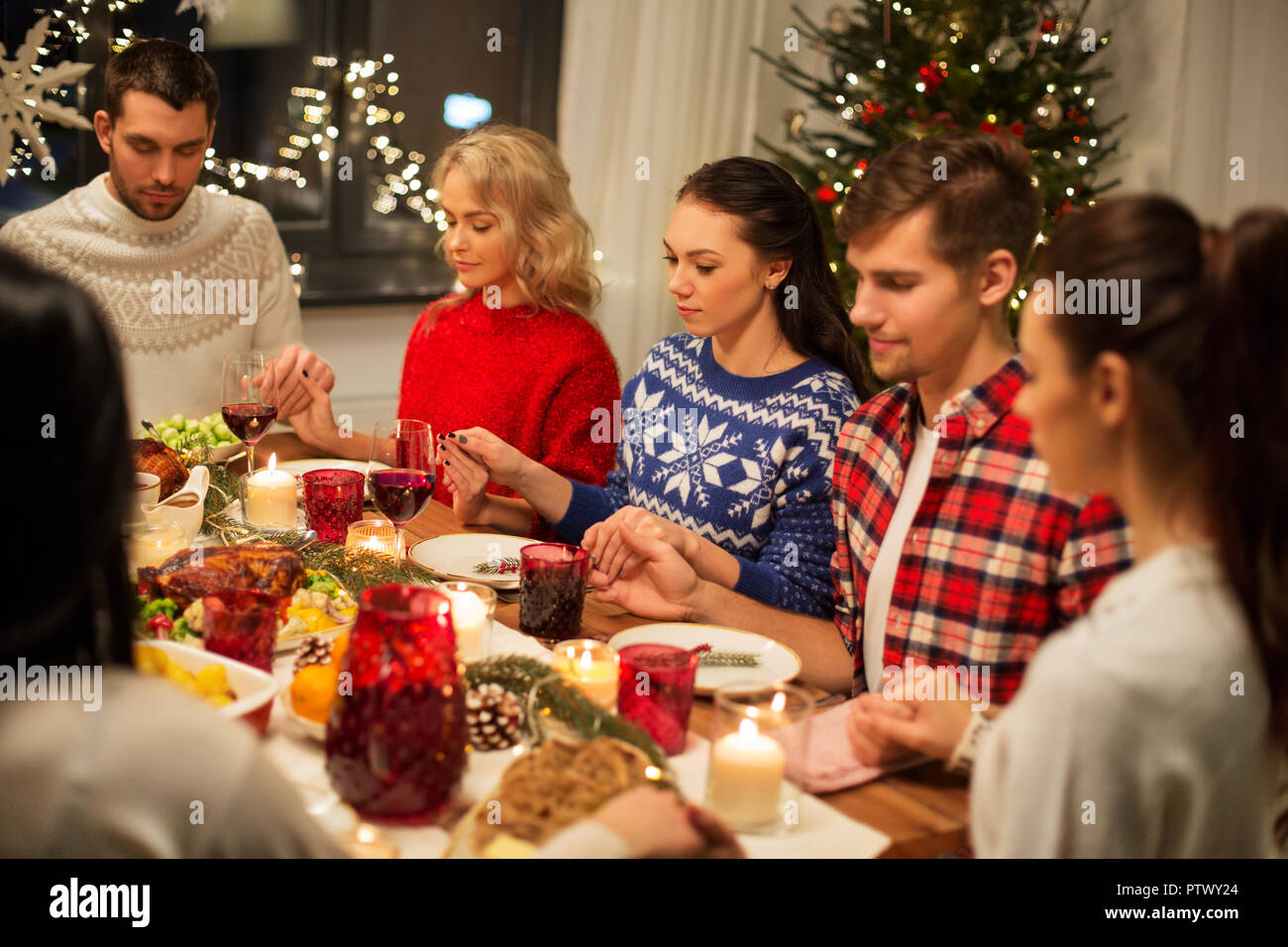 friends having home christmas dinner and praying Stock Photo