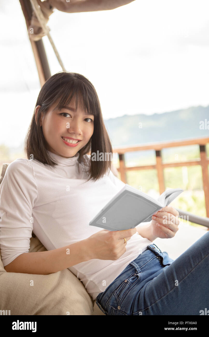 beautiful asian younger woman relaxing reading book on cradle Stock Photo