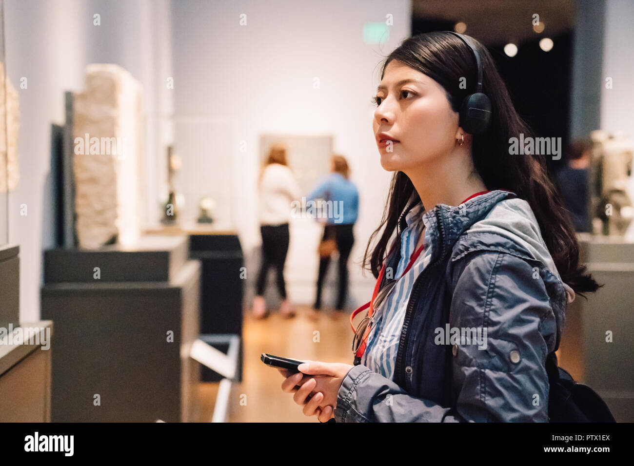 an elegant lady in the exhibition, wearing earphone to hear the voice guide Stock Photo