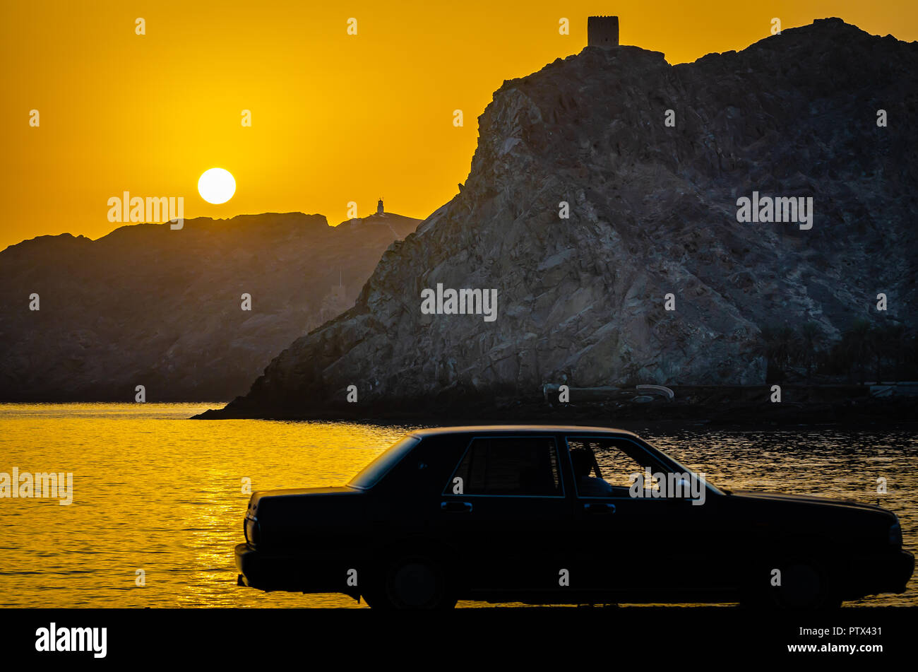 Golden Hour. Sun rising over mountains. Silhouette of a man in car watching. Stock Photo