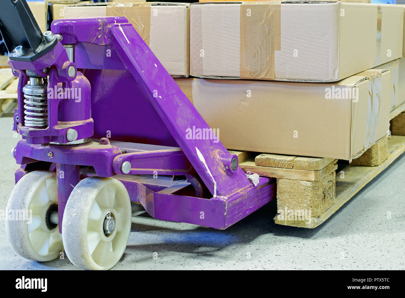 Purple hand pallet truck with cardboard boxes close up. Stock Photo