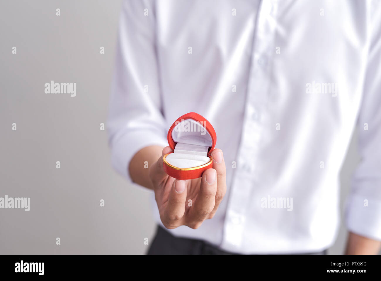 Handsome elegant man in a white shirt is holding a box with an engagement ring and shows in camera. Stock Photo