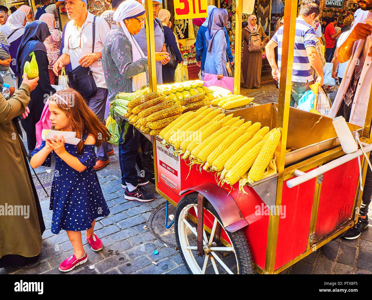 Istanbul, Turkey - July 11, 2018. A girl buying a corn cob at a street stall of Eminonu, a former district of Istanbul, Turkey. Stock Photo
