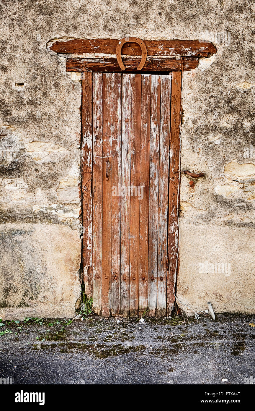 A small wooden door with a horseshoe at the top leads to an old cellar in the village of Santenay in the Burgundy region of France. Stock Photo