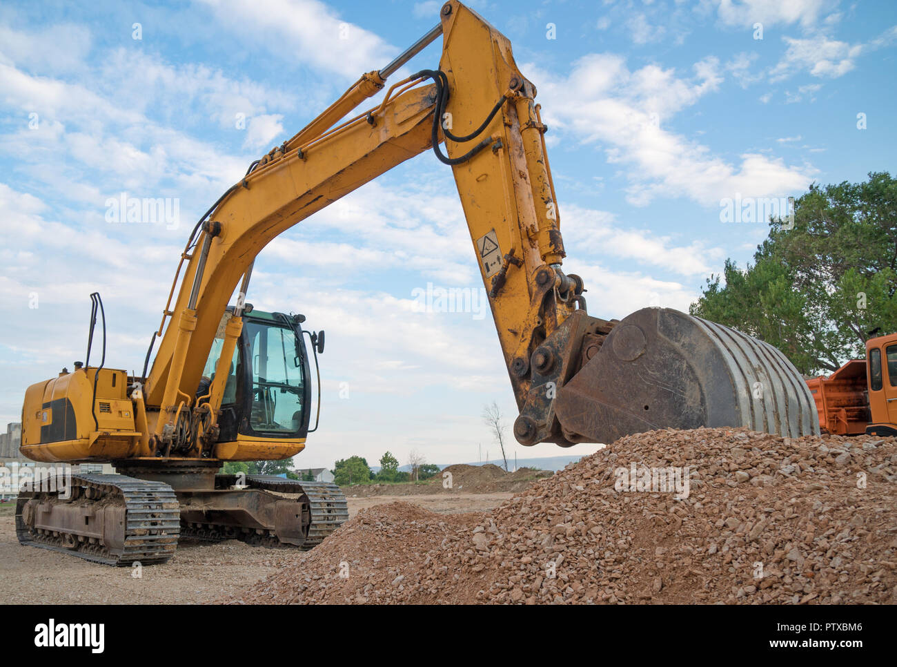 Yellow excavator working on the construction site Stock Photo - Alamy