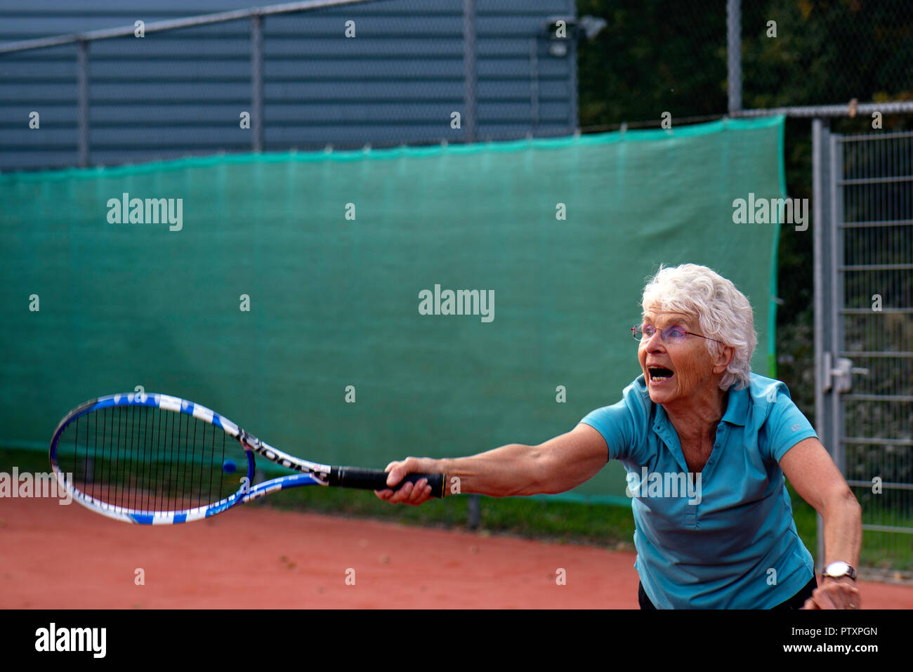 Sportive elderly woman playing tennis Stock Photo