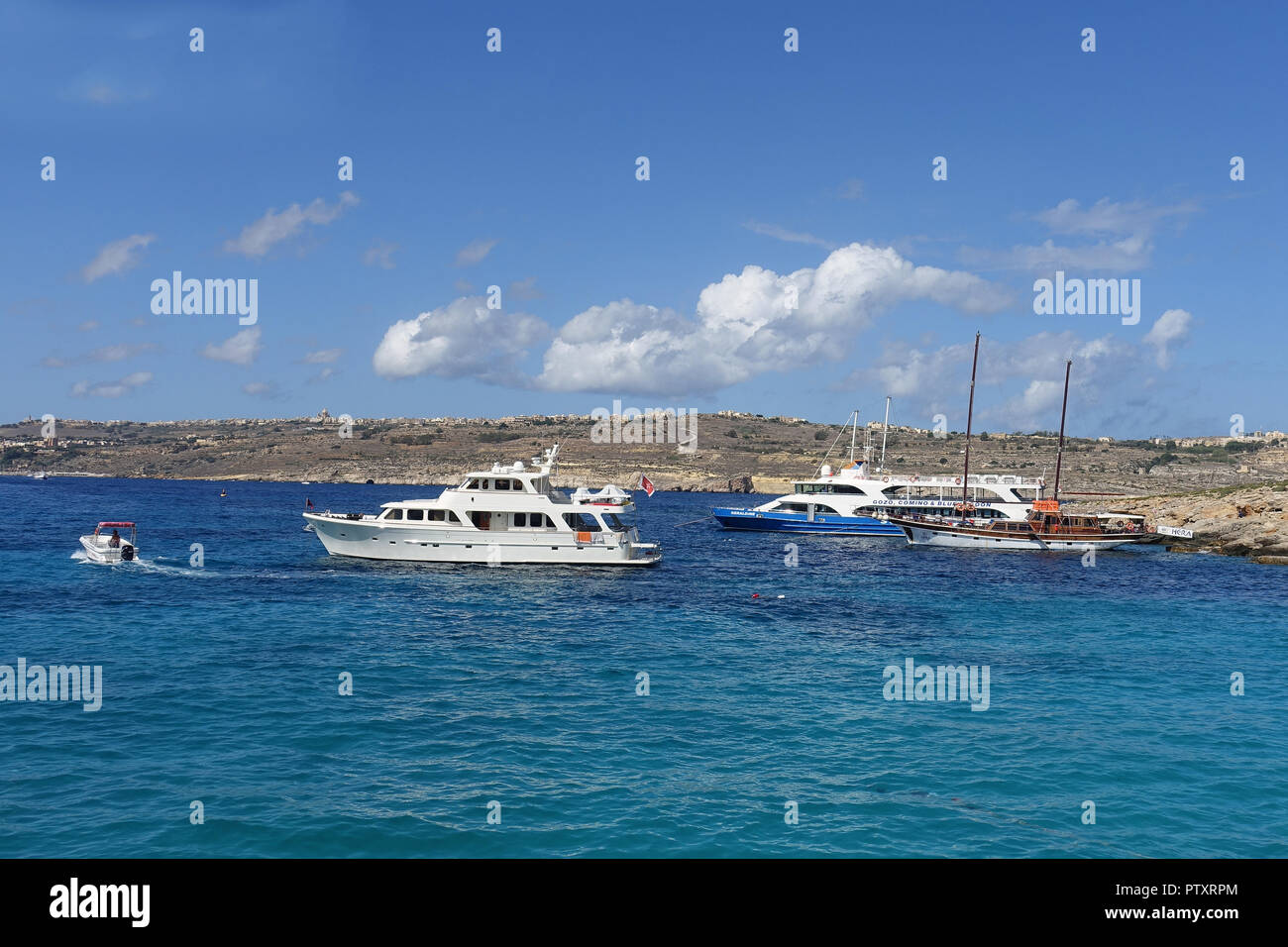 Private yachts and excursion boats moored in Blue Lagoon, Comino Island. The Lagoon is famed for its crystal-clear waters for swimming and diving Stock Photo