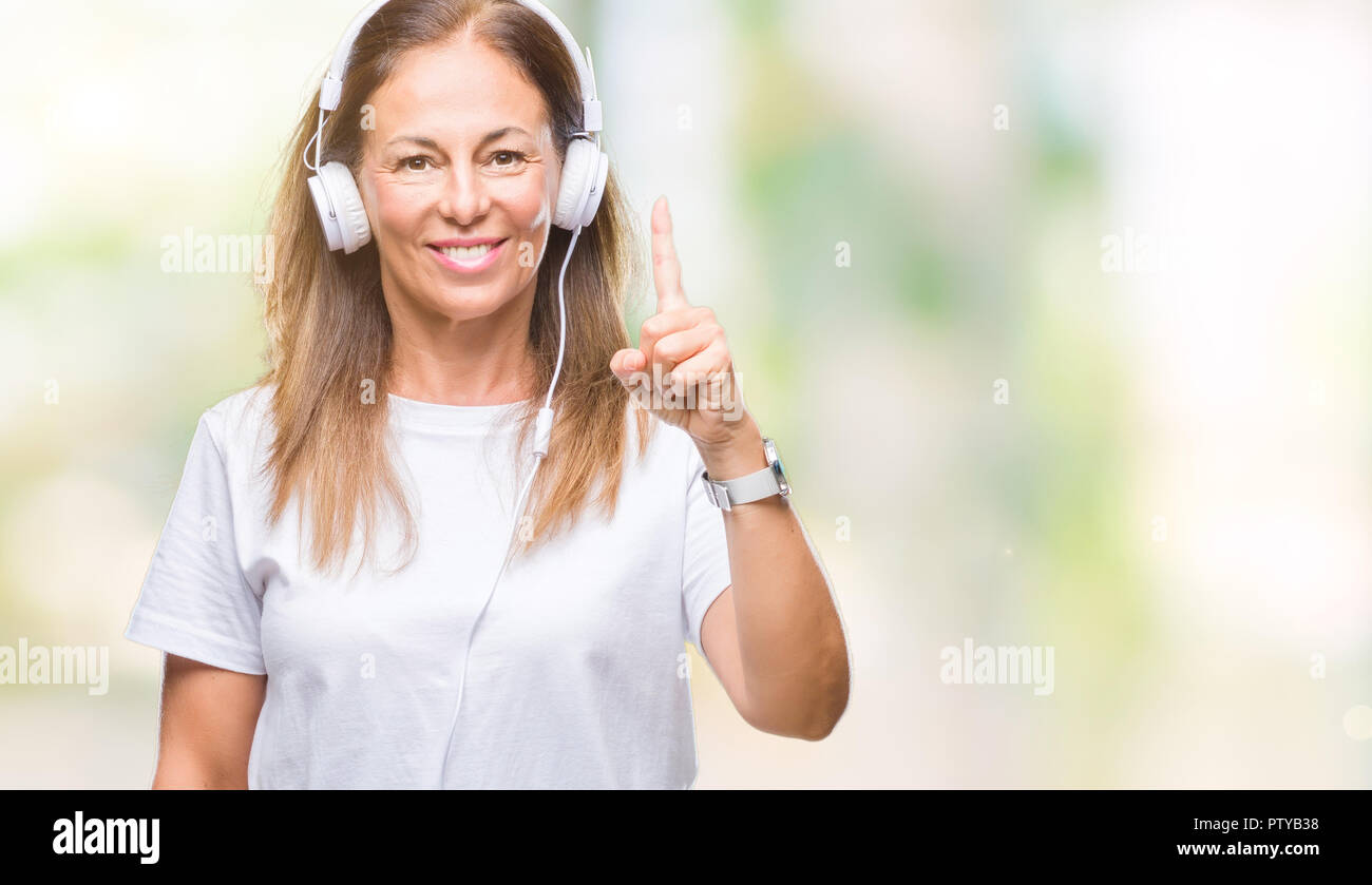 Middle age hispanic woman listening to music wearing headphones over ...