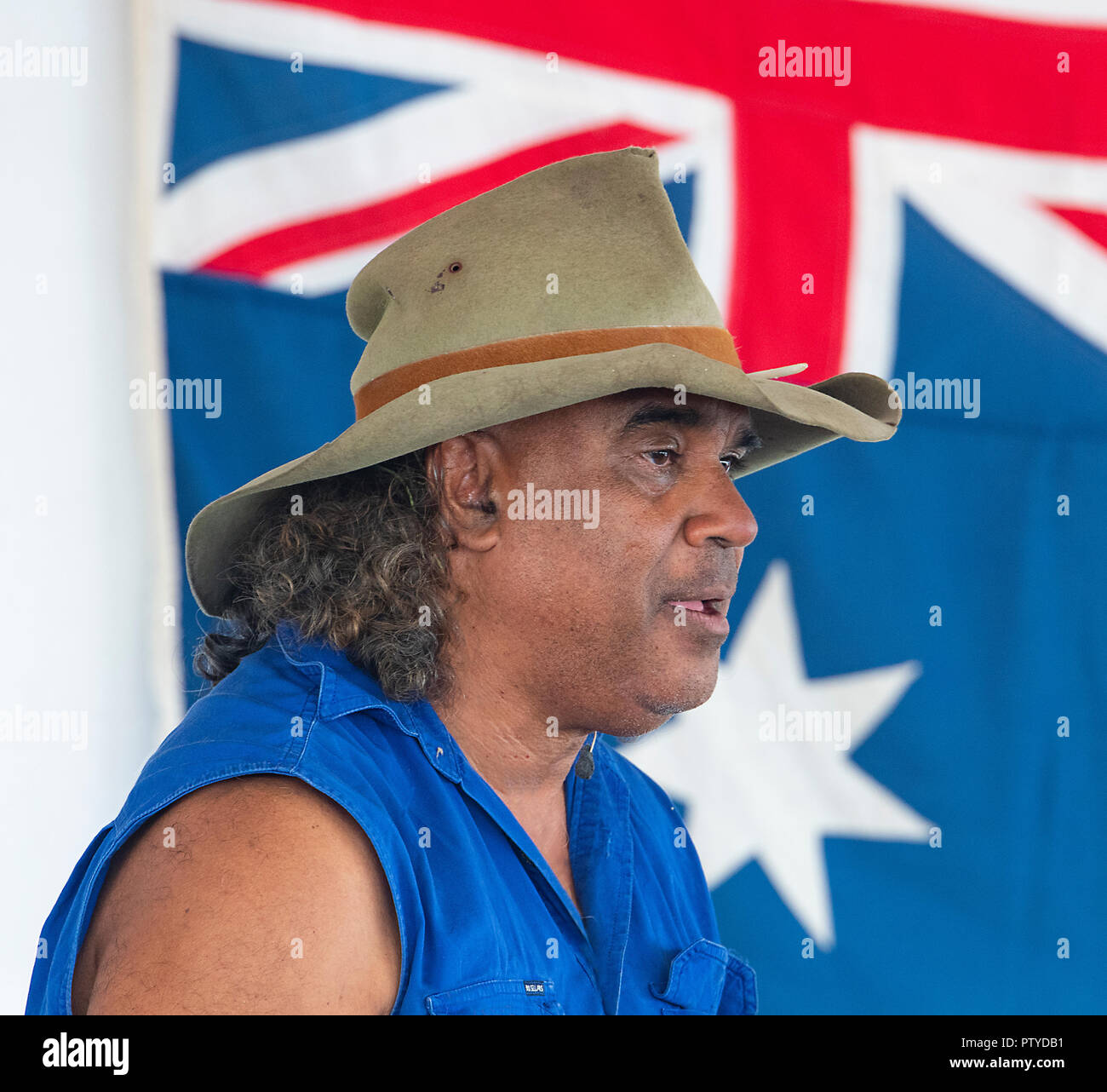 Portrait of David Hudson, an Aboriginal man, standing in front of the Australian flag performing at the Australian Camp Oven Festival 2018, Millmerran Stock Photo