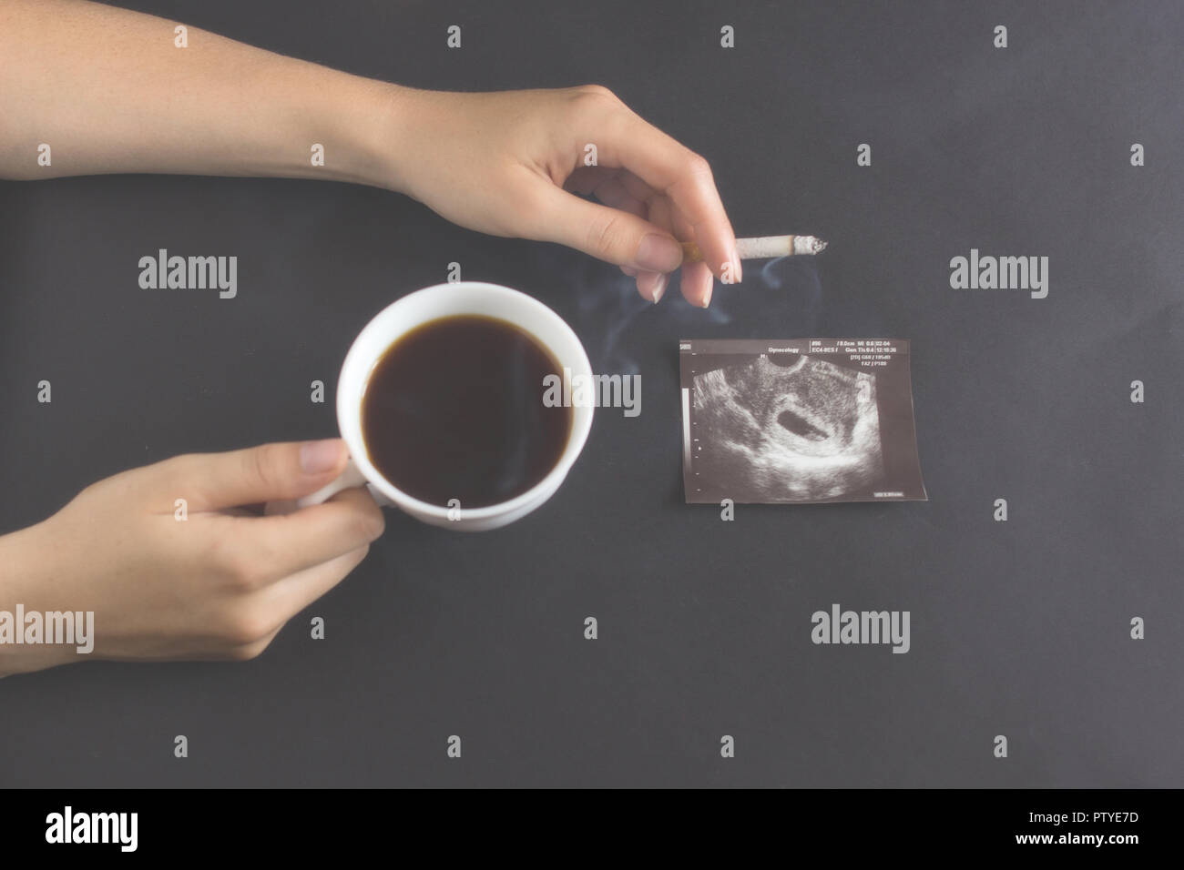 Female hands hold a cup of coffee and a burning cigarette, pregnancy