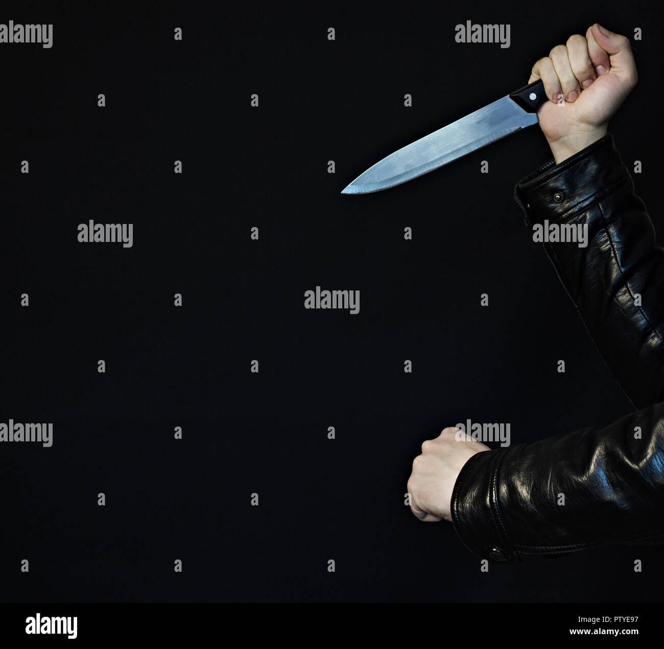 Male hands with a knife and fist on a black background, closeup Stock