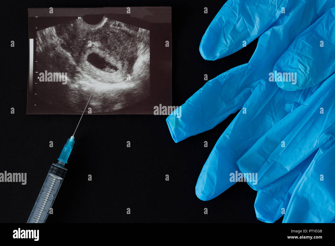 A picture of a uzi, a syringe, an abortion, medical gloves, a black background Stock Photo