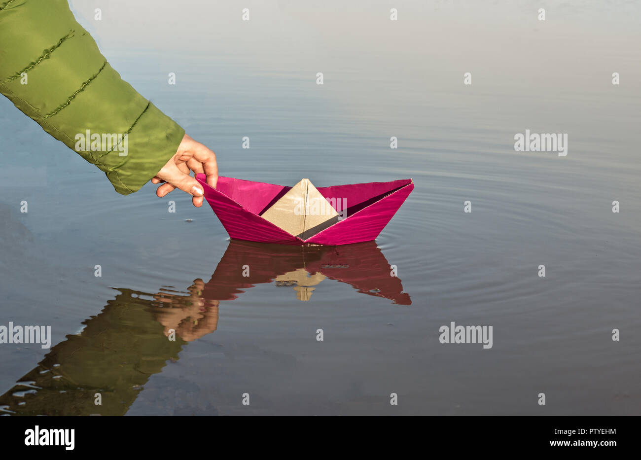 The girl is launching a red paper boat, close-up Stock Photo