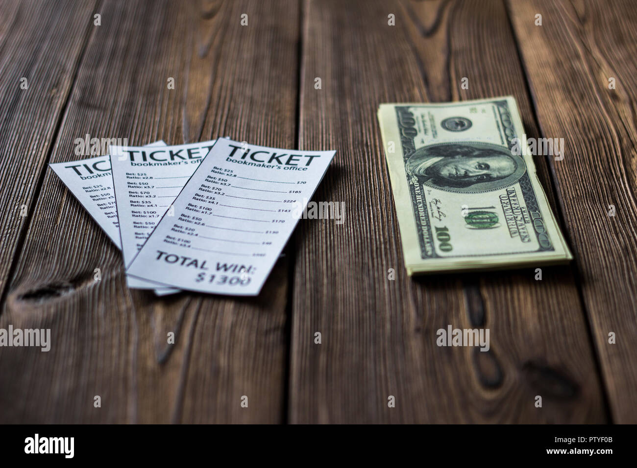 Tickets of the bookmaker office and money dollars lie on a wooden table, close-up Stock Photo