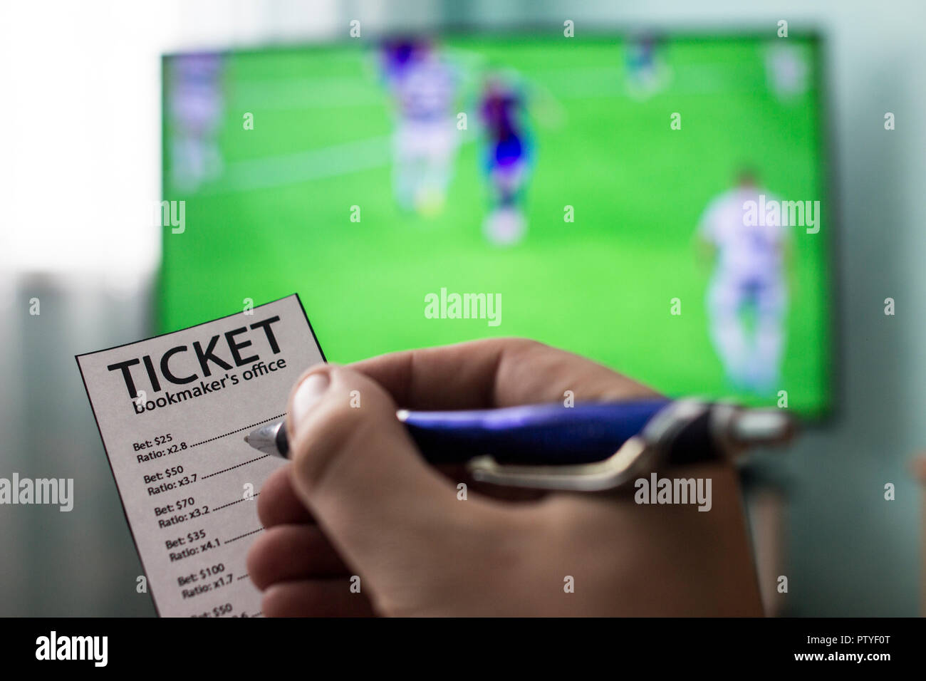 Men's hands with a ticket bookmaker's office, on TV show football, Champions League, sports betting, close-ups Stock Photo