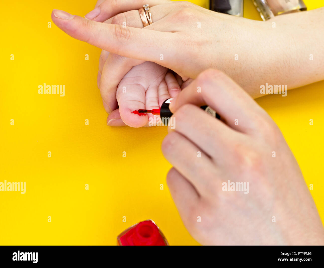 A mother paints her toenails with her little daughter, a yellow