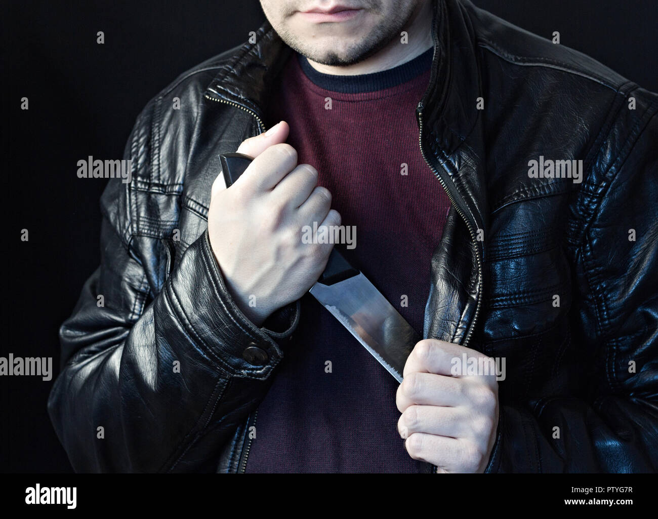 A man takes a knife out of a jacket, a black background Stock Photo