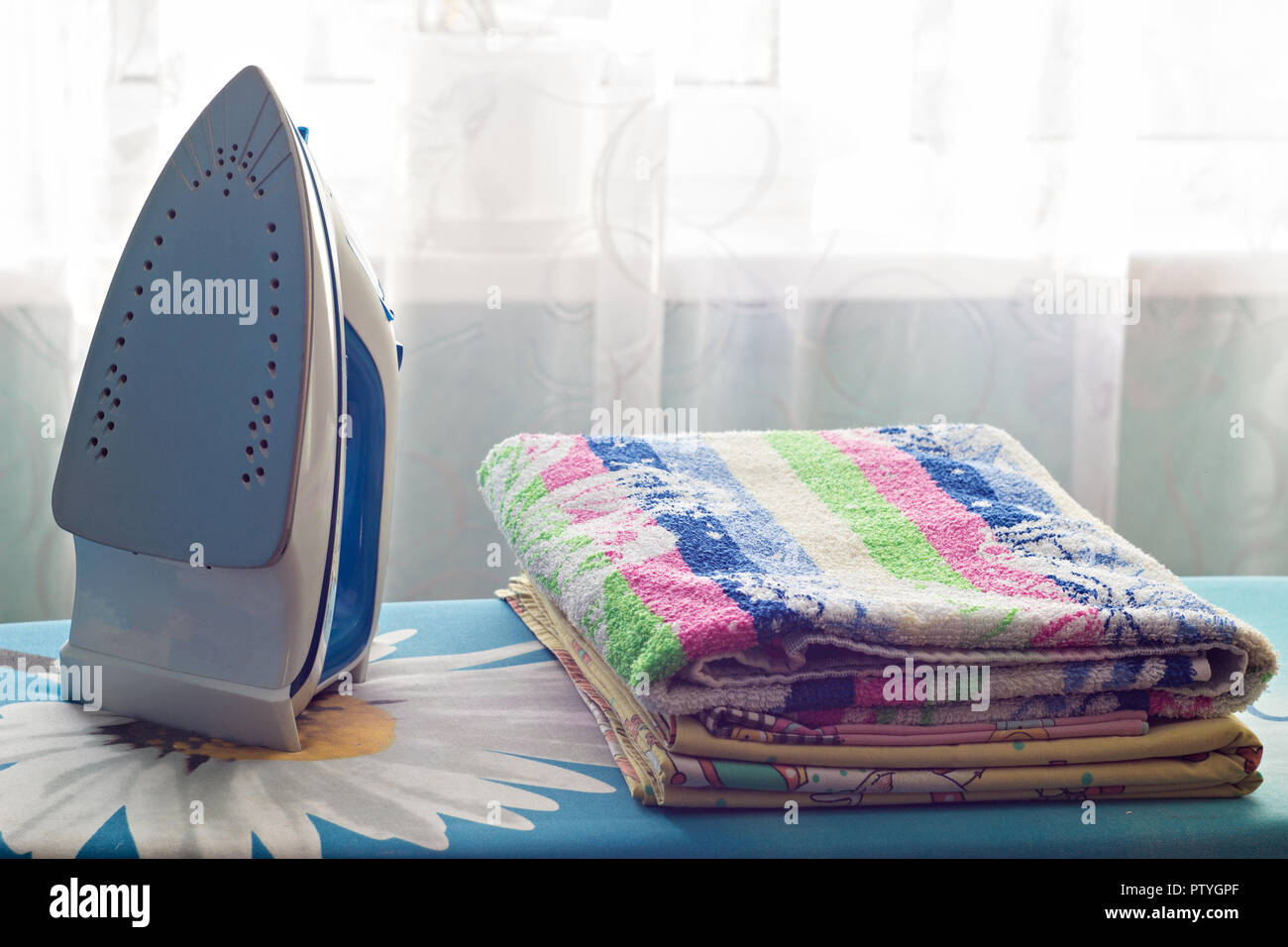 Iron and a stack of towels on the ironing board, close-up Stock Photo