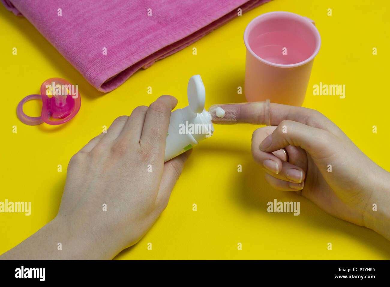 A mother puts toothpaste on a baby brush, brushing teeth Stock Photo
