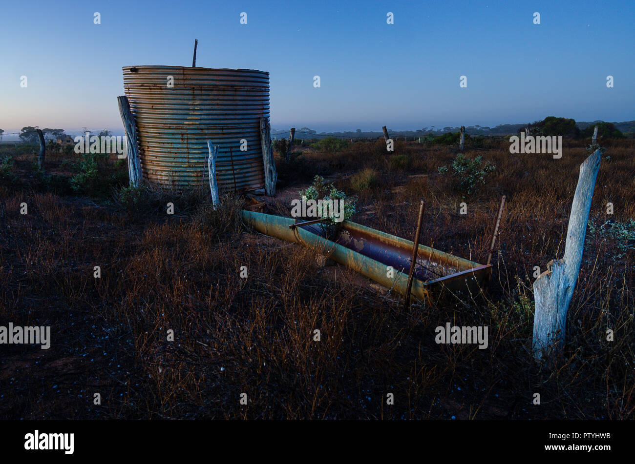 Rusted corrugated iron rainwater tank near old ruins on farm in early morning light near Ceduna South Australia Stock Photo