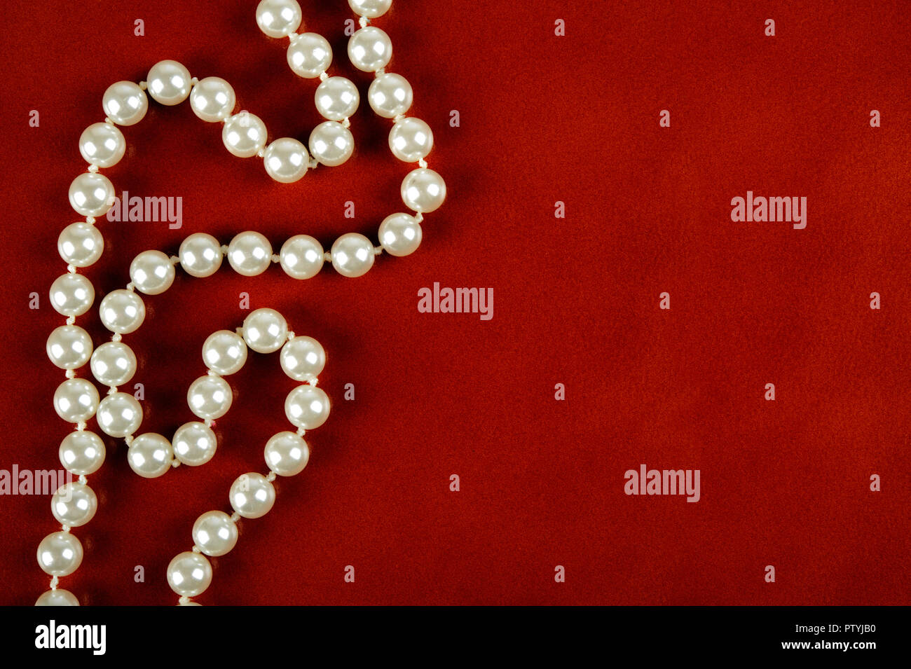 White pearl necklace on reddish brown leather background. Stock Photo