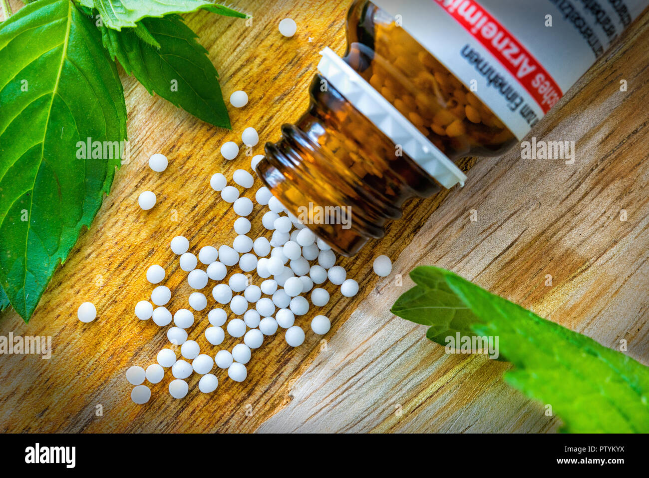 Globoli on wooden table with brown bottle and green leaves Stock Photo