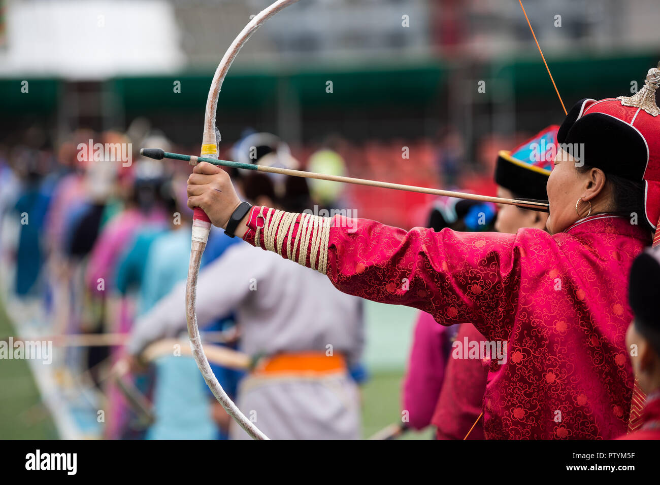 Naadam festival Mongolia archery, Mongolian women in traditional Mongolian dress shooting arrows with Mongol bow and arrow, colorful traditional costu Stock Photo