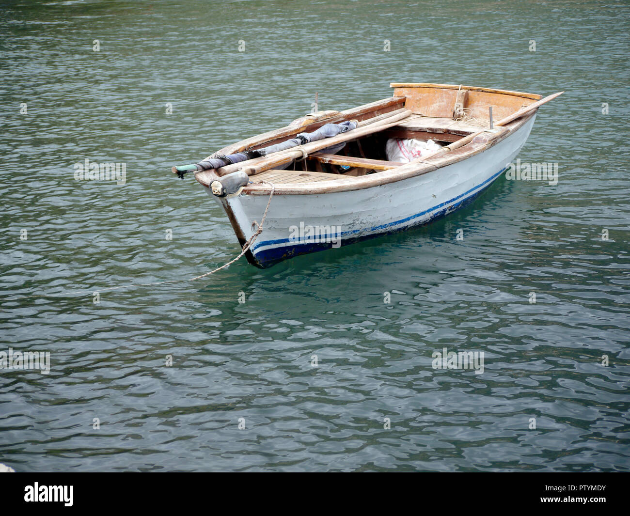 Small, old, battered, wooden dinghy with oars and folded home-made