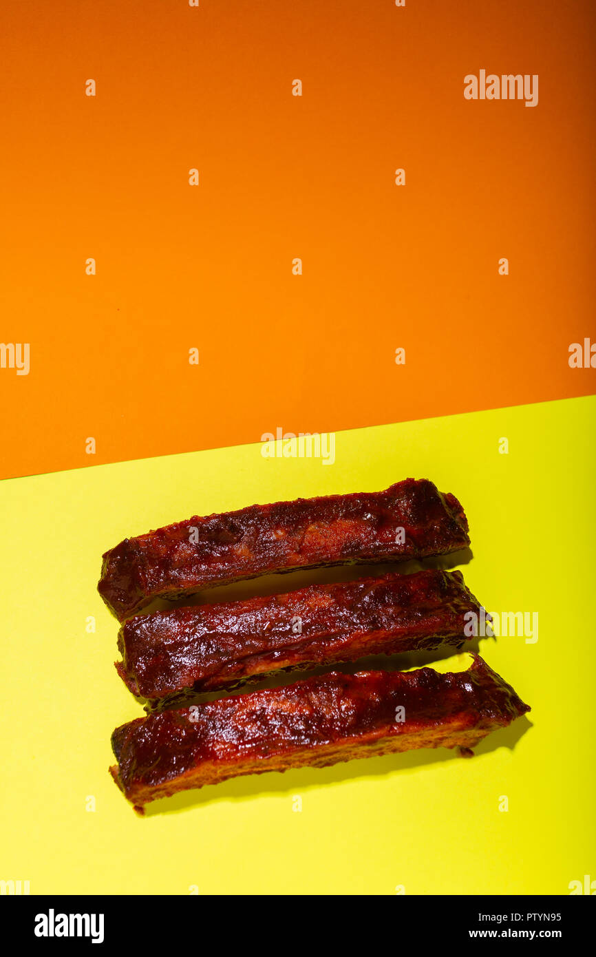 Barbecued and marinated sticky spare rib on yellow and orange background with copy space. Stock Photo