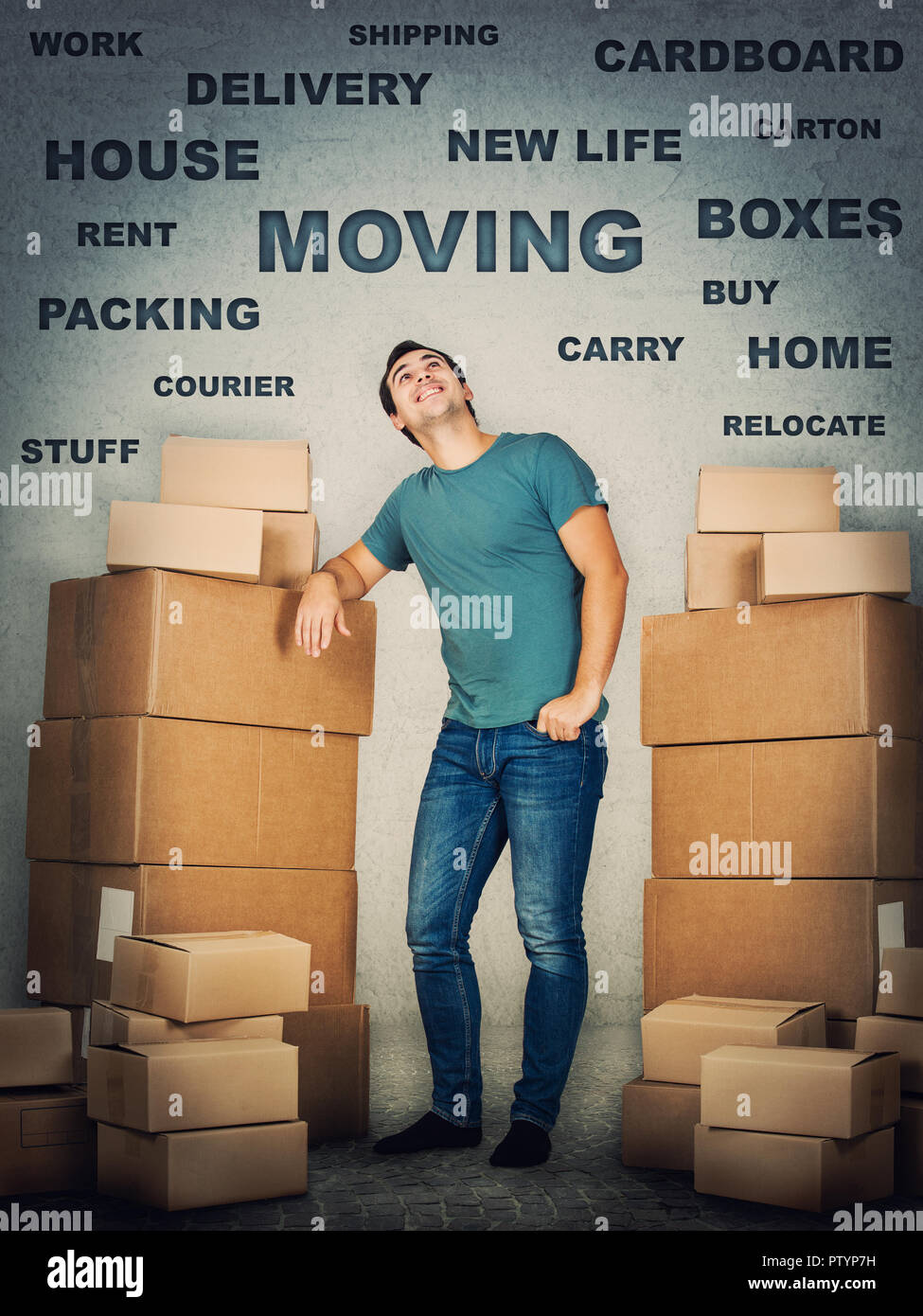 Full length portrait of young man leaning on cardboard boxes thoughtful looking up. House move concept, packing stuff isolated over grey wall. Stock Photo