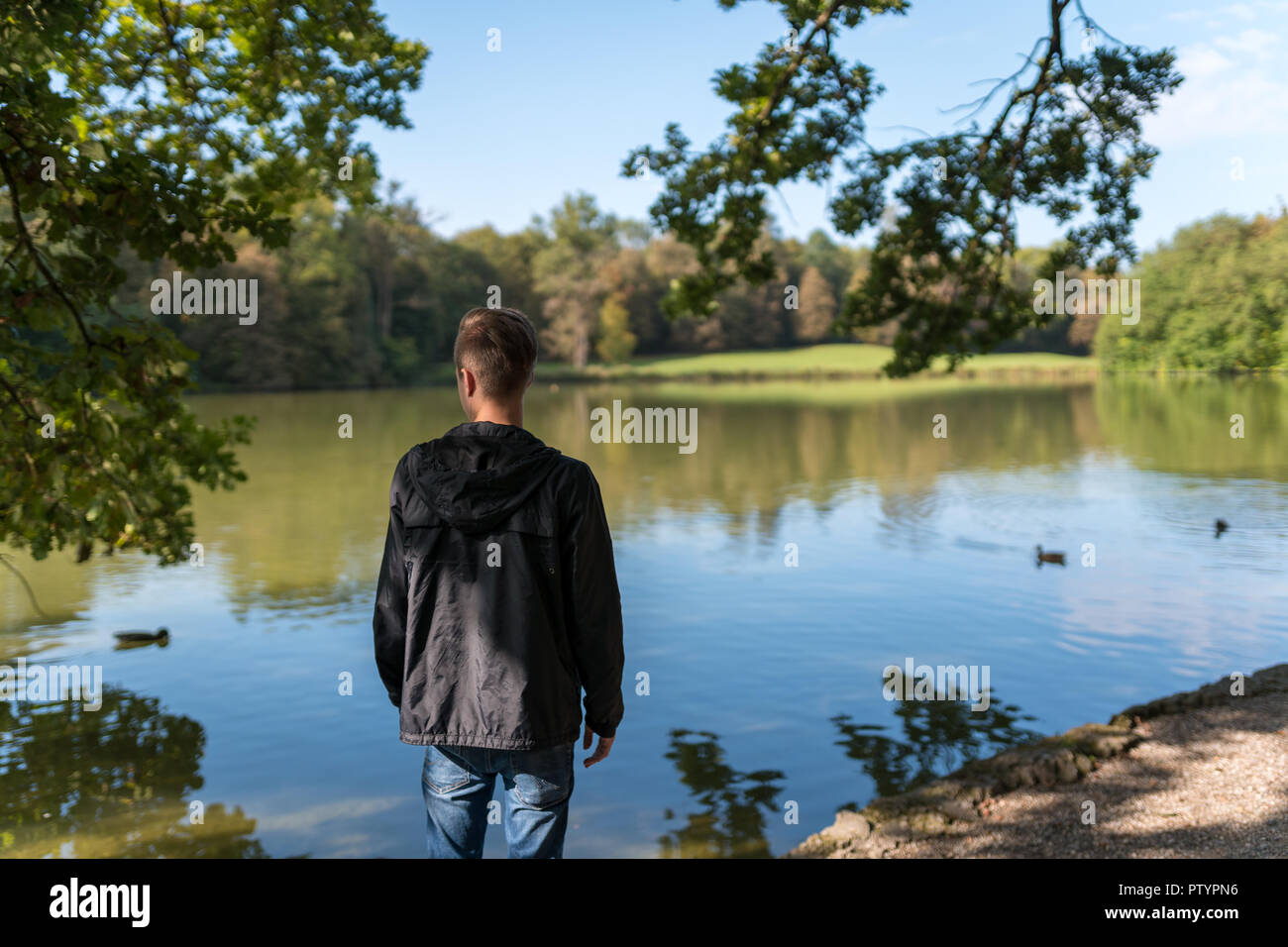 Lonely young man standing in front of a lake in germany. Stock Photo