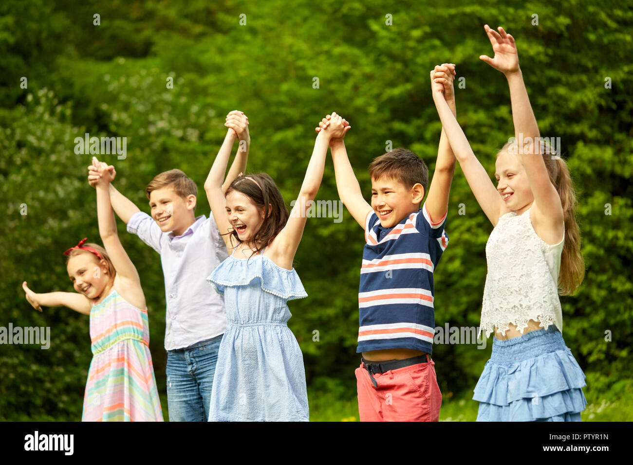 happy kids holding raised hands in summer park Stock Photo - Alamy